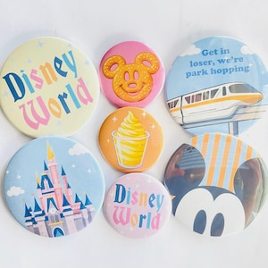 May include: A collection of seven circular pin-back buttons featuring various designs including the text Disney World, a yellow Mickey-shaped pretzel, a monorail with the text Get in loser, we're park hopping, a castle, a Dole Whip, and Mickey ears.