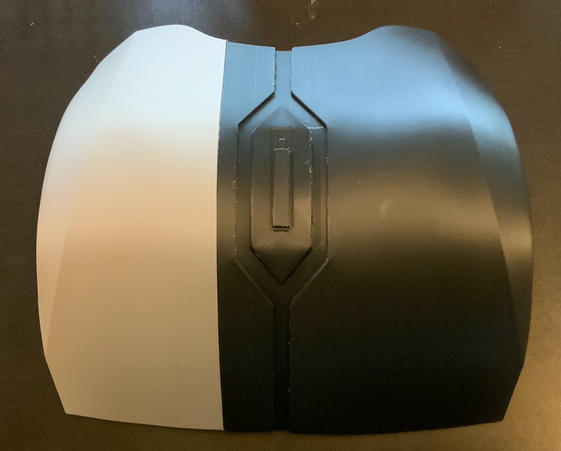Puede incluir: Una pieza de pecho impresa en 3D para cosplay o la fabricaci&oacute;n de disfraces. La pieza est&aacute; hecha de dos mitades, una blanca y una negra, y presenta un dise&ntilde;o geom&eacute;trico.