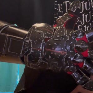 May include: A black and red robotic arm with a detailed design. The arm features articulated fingers and a textured surface, with accents of red. The overall aesthetic suggests a futuristic or sci-fi theme.