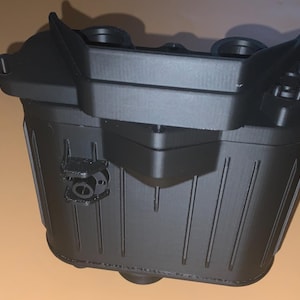 May include: A black plastic box with a ribbed texture and a small latch on the side. The box is rectangular in shape and has a flat top.