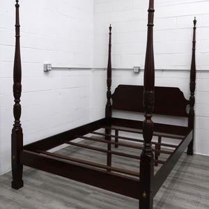 May include: A dark mahogany four-poster bed frame. The bed features ornate carvings on the posts and headboard. The frame is made of wood and has a classic design, suitable for a bedroom.