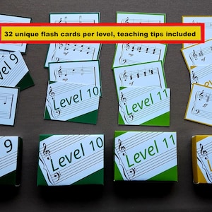 May include: Four boxes of flash cards for learning music. The boxes are labeled Level 9, Level 10, Level 11, and Level 12. Each box has a green and white design with musical notes. The text "32 unique flash cards per level, teaching tips included" is written in yellow on a red background.