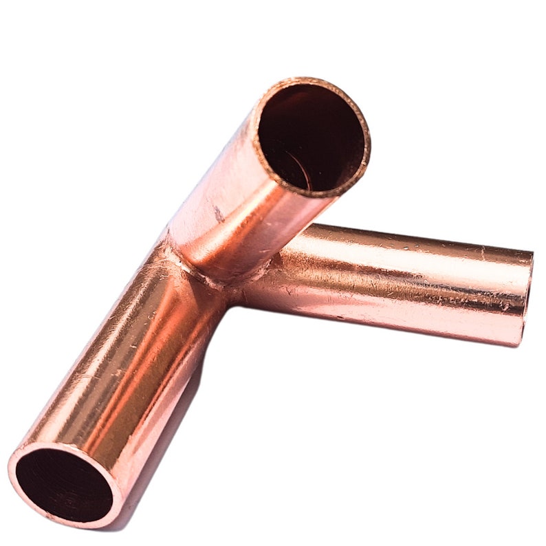 May include: A metallic copper pipe fitting shaped as a ninety-degree elbow connector. The object features a smooth, reflective surface with a reddish-brown hue and two open cylindrical ends designed for joining pipes in a plumbing system.