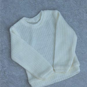 May include: Ivory-colored sweater with a crew neck and long sleeves. The knitwear has a ribbed texture and a relaxed fit. This cozy sweater is perfect for casual wear.