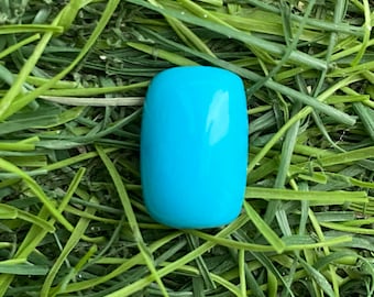 May include: A single, smooth, rectangular bead with rounded corners and a vibrant, solid turquoise blue color. The bead has a polished, glossy finish that reflects light evenly across its curved surface, highlighting its uniform shape and color.