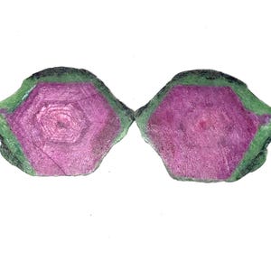 Könnte beinhalten: Zwei Scheiben aus Rubin in Zoisit mit einem leuchtend magentafarbenen hexagonalen Kern, der von einem texturierten grünen Mineralrand umgeben ist. Diese flachen, polierten Mineralexemplare zeigen natürliche Kristallstrukturen.