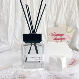 May include: A clear glass diffuser bottle with a black wooden lid and black diffuser sticks. The bottle has a label that reads "Arosydday Flowers & Diffusers".