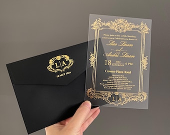 May include: A black envelope with a gold foil monogram and date, paired with a clear acrylic invitation featuring an ornate gold frame design. The text includes details for a 25th wedding anniversary celebration for Lisa and Anders Larsen on May 18, 2024.