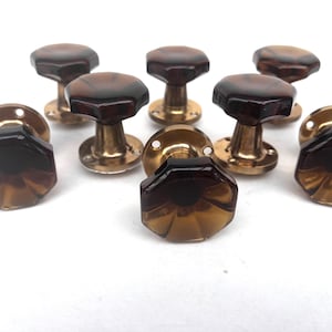 May include: Set of eight vintage door knobs. Each knob features a faceted, amber-colored glass top and a brass base. The knobs are octagonal and have a classic, antique design, suitable for interior doors.