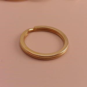 May include: A gold-coloured metal key ring with a double-ring design.