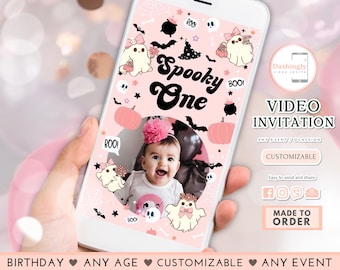 May include: A pink and black digital video invitation for a spooky one-year-old birthday party. The invitation features a cute cartoon ghost, a pumpkin, and a cauldron. The text "Spooky One" is in black and white with a pink background. The invitation is customisable and easy to send and share.