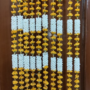 May include: A set of 10 decorative door garlands made of yellow and white artificial flowers. Each garland has a gold tassel at the bottom.