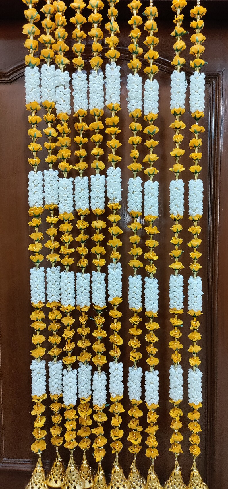 May include: A set of 10 decorative door garlands made of yellow and white artificial flowers. Each garland has a gold tassel at the bottom.