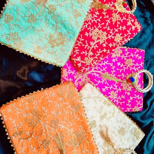 May include: Five embroidered fabric bags with gold trim and tassels. The bags are in various colors, including green, red, pink, orange, and white. Each bag has a circular handle.