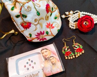 May include: A white satin pouch with floral embroidery, a set of pearl earrings with a red and gold design, a red flower, and a package of colorful bindi stickers with the text "Roop Nikhar Bindi".