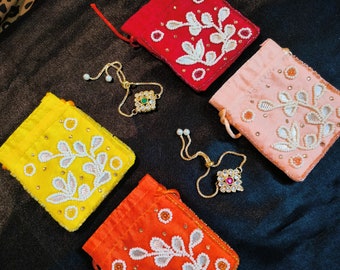 May include: Four small pouches with embroidered floral designs in yellow, orange, red, and pink. The pouches are made of fabric and have a drawstring closure. There are also two gold bracelets with jeweled charms.