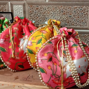 May include: Four drawstring bags with floral patterns and pearl trim. The bags are in shades of blue, green, red, and pink.