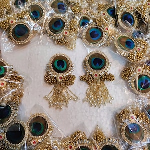 Op de afbeelding: Assortiment van pauwenveer oorbellen met gouden accenten en parelversiering. De oorbellen zijn verpakt in doorzichtige plastic zakjes. De afbeelding bevat ook de tekst "WhatsApp 919873884606".
