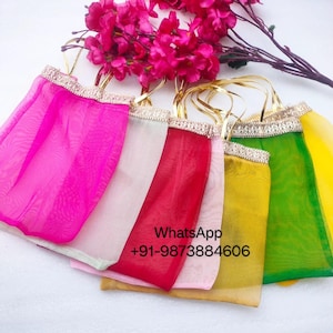 Può includere: Una collezione di borse in tessuto trasparente colorato con manici e finiture dorate. Le borse sono in tonalità di rosa, rosso, verde e giallo. L'immagine include anche fiori rosa e il testo "WhatsApp +91-9873884606".