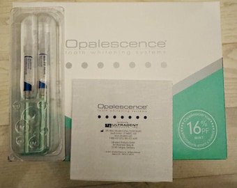 Peut inclure: Une boîte blanche et sarcelle de systèmes de blanchiment des dents Opalescence avec un emballage blister en plastique transparent contenant deux seringues. Une carte d'instructions carrée blanche avec du texte noir est placée devant la boîte.