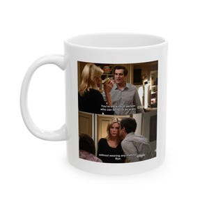 Può includere: Una tazza in ceramica bianca con una foto di una scena dello show televisivo Modern Family. La foto mostra tre personaggi, due donne e un uomo, con il testo "You're the kind of person who can be twice as scary without wearing any makeup. Bye."
