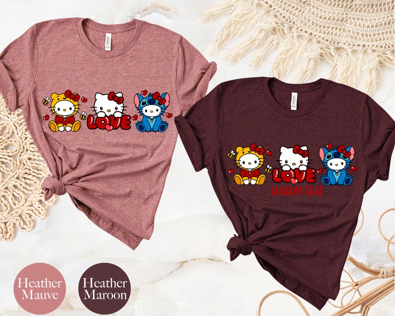 May include: Two t-shirts, one heather mauve and one heather maroon, each featuring a graphic of three cartoon characters. The characters are dressed as a bee, Hello Kitty, and Stitch, with the word "LOVE" in the center. The text "CUSTOM TEAM" is below the word "LOVE" on the maroon shirt.