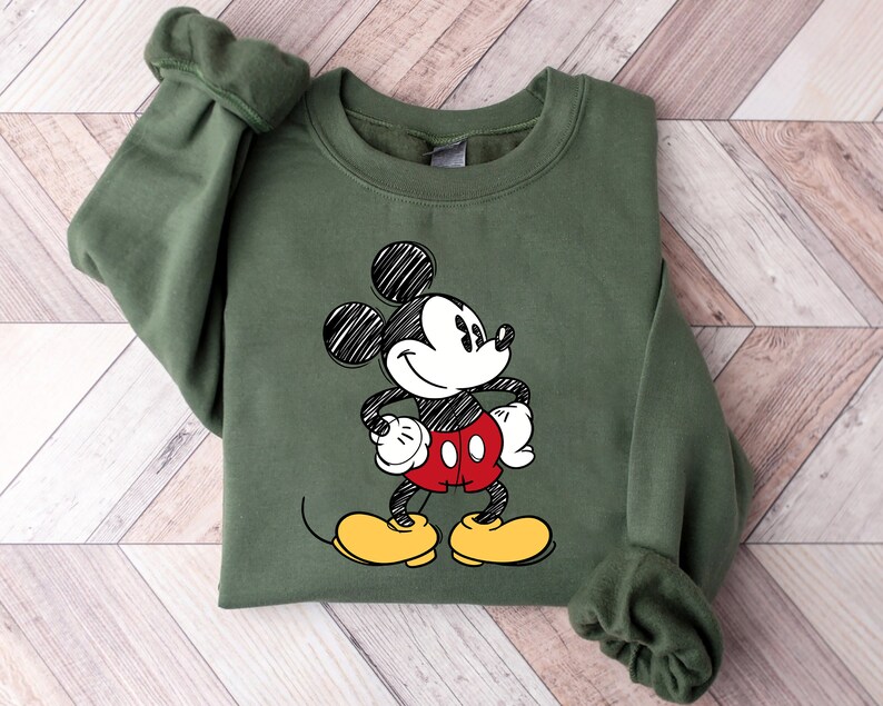May include: A green sweatshirt with a black and white sketch of Mickey Mouse wearing red shorts and yellow shoes.