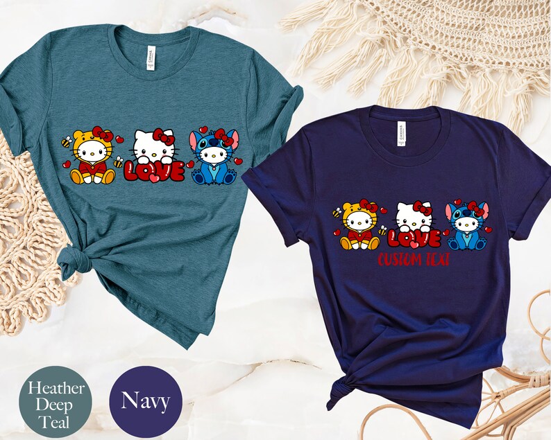 May include: Two t-shirts, one heather deep teal and one navy, featuring a cartoon design. The design includes three characters, Hello Kitty and Stitch, with the word "LOVE" in red. The navy shirt has the text "CUSTOM TEXT" below the word "LOVE".