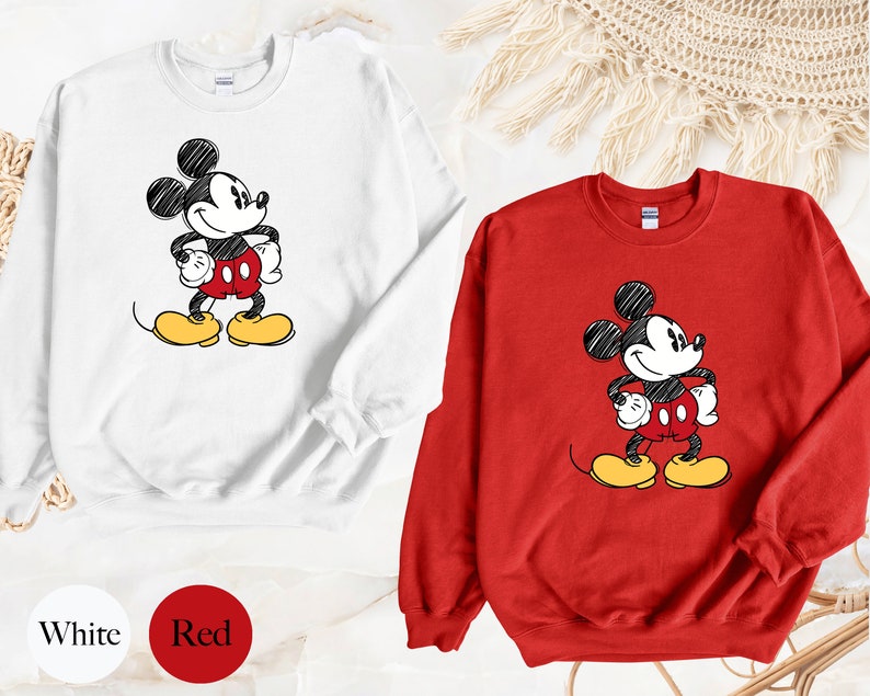 May include: Two sweatshirts with a cartoon drawing of Mickey Mouse. One sweatshirt is white and the other is red.