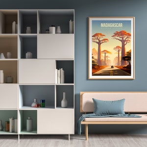 May include: A framed poster with a vintage travel illustration of a road lined with tall trees in Madagascar. The poster reads "MADAGASCAR, BAOBAB AVENUE".