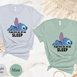 K&ouml;nnte beinhalten: Zwei T-Shirts mit einer blauen Comicfigur. Die Figur liegt und sagt "Wenn du mich liebst, lass mich schlafen". Ein Shirt ist hellblau und das andere ist mintgr&uuml;n.
