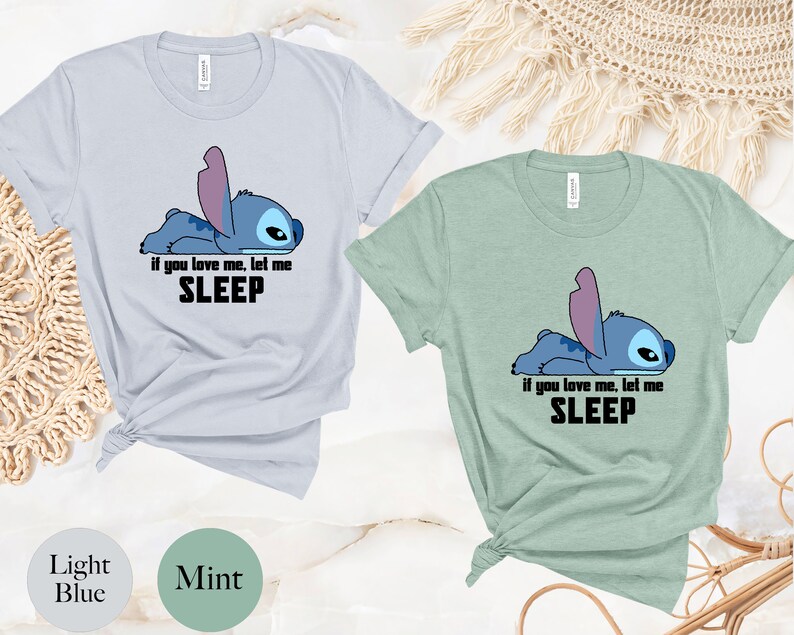 K&ouml;nnte beinhalten: Zwei T-Shirts mit einer blauen Comicfigur. Die Figur liegt und sagt "Wenn du mich liebst, lass mich schlafen". Ein Shirt ist hellblau und das andere ist mintgr&uuml;n.