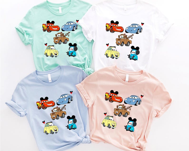 May include: Four different colored t-shirts with a Cars and Mickey Mouse theme. The shirts are light blue, light green, white, and pink. Each shirt features a different combination of Cars characters, including Lightning McQueen, Mater, and Tow Mater. Mickey Mouse is featured on each shirt with a different colored hat.