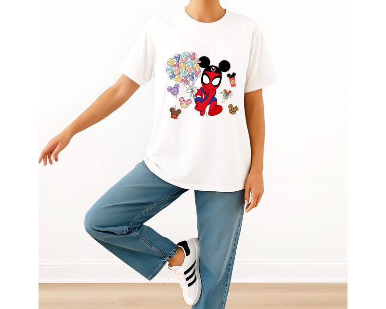 Puede incluir: Camiseta blanca con un personaje de dibujos animados que combina a Spider-Man y Mickey Mouse, sosteniendo globos de colores. La camiseta se combina con vaqueros azules y zapatillas blancas.