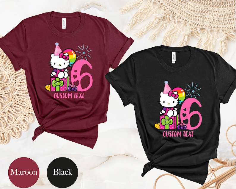 May include: Two t-shirts, one maroon and one black, featuring a cartoon Hello Kitty wearing a party hat and holding a balloon. The shirts have a pink number six and the text "CUSTOM TEXT" printed on them.