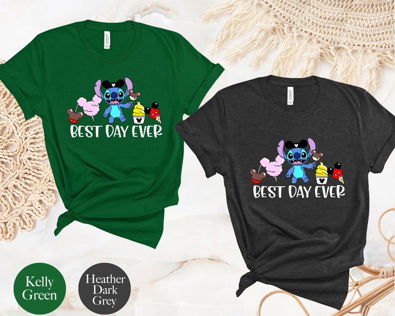 May include: Two t-shirts with a blue Stitch character wearing a Mickey Mouse hat and holding a pink cotton candy, a brown Mickey Mouse ear, a yellow ice cream cone, and a red Mickey Mouse ear. The text "Best Day Ever" is printed below the character. The t-shirt on the left is Kelly green and the t-shirt on the right is heather dark grey.