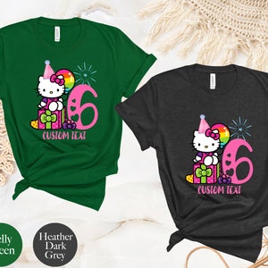 May include: Two t-shirts with a Hello Kitty design. The green shirt has a pink Hello Kitty with a party hat and a balloon. The grey shirt has a pink Hello Kitty with a party hat and a balloon. Both shirts have the number 6 and the text "CUSTOM TEXT".