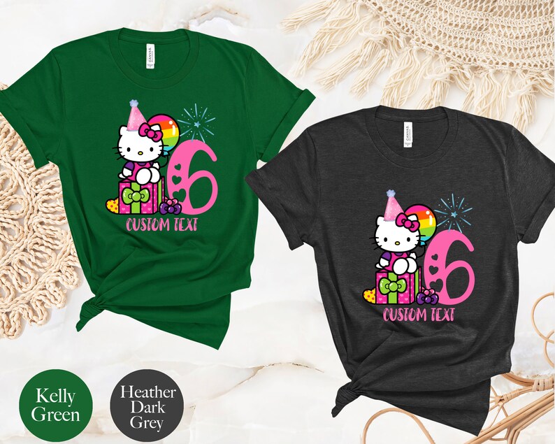 May include: Two t-shirts with a Hello Kitty design. The green shirt has a pink Hello Kitty with a party hat and a balloon. The grey shirt has a pink Hello Kitty with a party hat and a balloon. Both shirts have the number 6 and the text "CUSTOM TEXT".