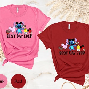 May include: Two t-shirts with a blue Stitch character from Lilo & Stitch. The Stitch character is holding a Mickey Mouse ice cream cone and surrounded by other Mickey Mouse themed treats. The text on the shirts reads "Best Day Ever". The shirts are pink and red.