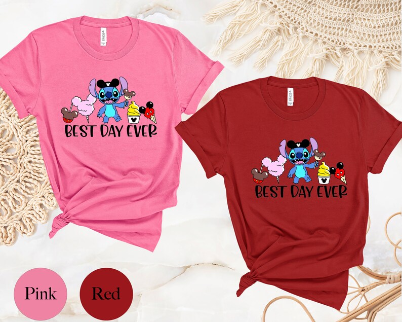 May include: Two t-shirts with a blue Stitch character from Lilo & Stitch. The Stitch character is holding a Mickey Mouse ice cream cone and surrounded by other Mickey Mouse themed treats. The text on the shirts reads "Best Day Ever". The shirts are pink and red.