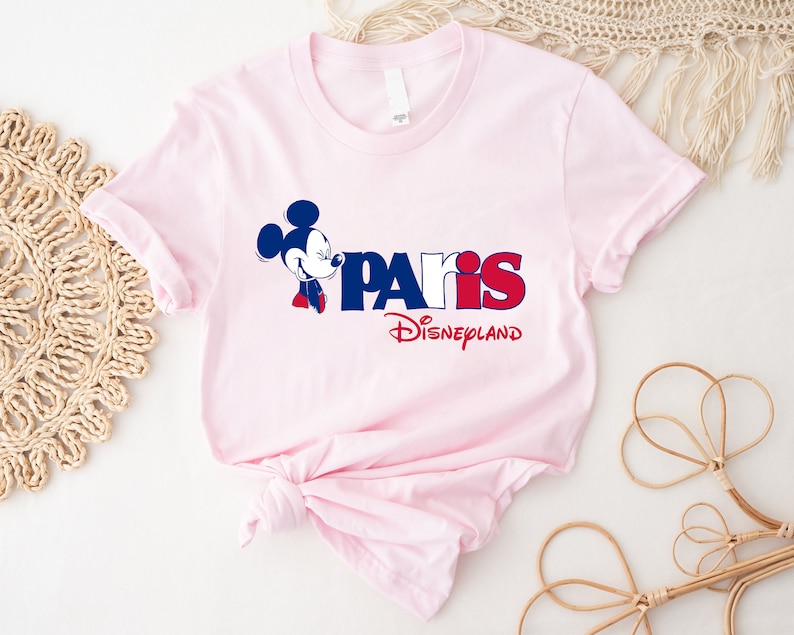 Puede incluir: Camiseta rosa con un gr&aacute;fico azul y rojo de Mickey Mouse y el texto "Paris Disneyland".