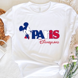 Puede incluir: Camiseta blanca con un gr&aacute;fico azul y rojo de Mickey Mouse y el texto "Paris Disneyland".