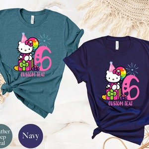 May include: Two t-shirts with a Hello Kitty design. The shirt on the left is teal and the shirt on the right is navy. Both shirts feature Hello Kitty wearing a party hat and holding a balloon. The number 6 is on both shirts. The text "CUSTOM TEXT" is on both shirts.