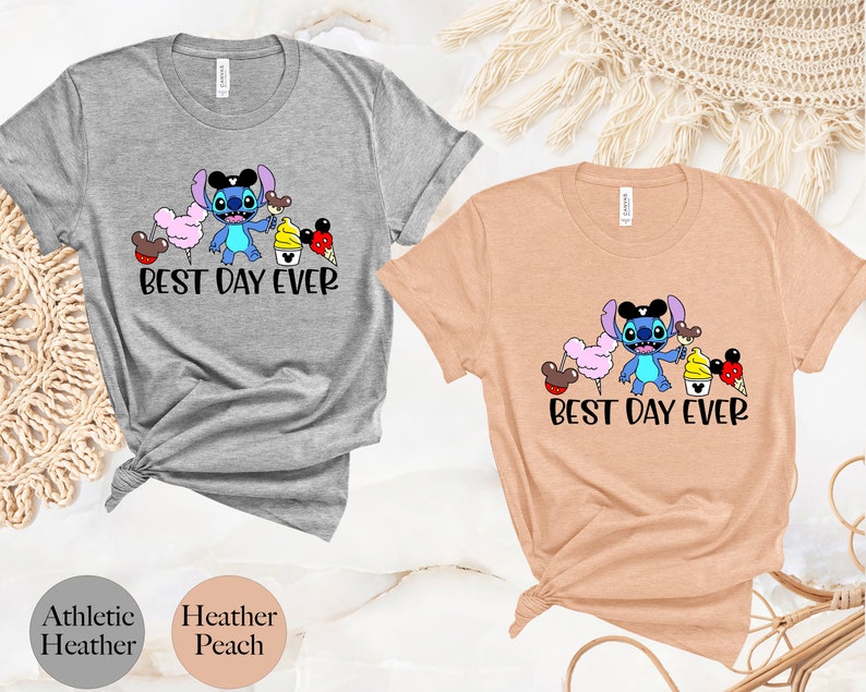May include: Two t-shirts with a cartoon Stitch character holding a Mickey Mouse ice cream cone. The text "Best Day Ever" is printed on both shirts. The shirts are available in athletic heather and heather peach.