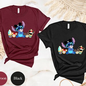 Pode incluir: T-shirts bord&ocirc; e pretas com um personagem de desenho animado com &oacute;culos e gravata borboleta, rodeado de sobremesas. O personagem &eacute; azul com orelhas grandes. As t-shirts s&atilde;o de manga curta.
