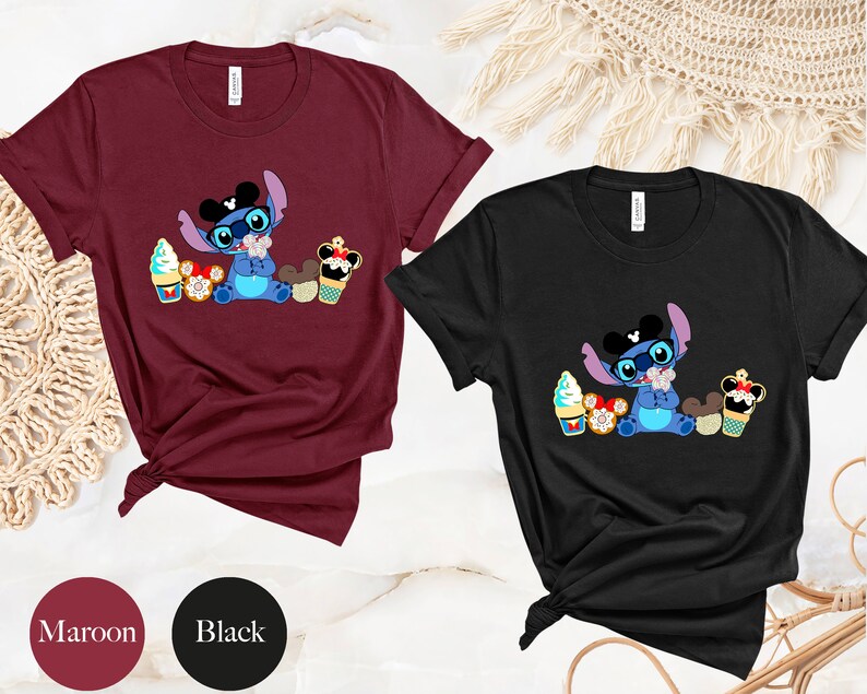 Pode incluir: T-shirts bord&ocirc; e pretas com um personagem de desenho animado com &oacute;culos e gravata borboleta, rodeado de sobremesas. O personagem &eacute; azul com orelhas grandes. As t-shirts s&atilde;o de manga curta.