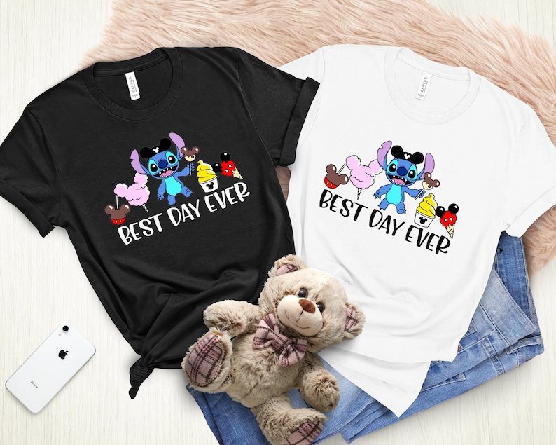 May include: Two t-shirts with a blue Stitch character holding a Mickey Mouse ice cream cone and other Disney treats. The text on the shirts reads "Best Day Ever".