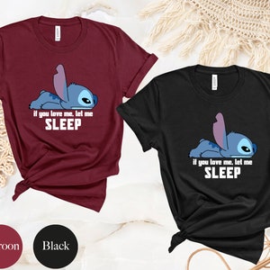 K&ouml;nnte beinhalten: Zwei T-Shirts mit einer Zeichentrickfigur Stitch aus Lilo & Stitch. Das weinrote T-Shirt hat den Text "Wenn du mich liebst, lass mich SCHLAFEN". Das schwarze T-Shirt hat den gleichen Text.