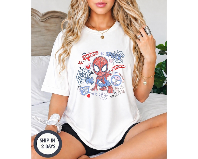 Puede incluir: Camiseta blanca con un dise&ntilde;o de Spider-Man de dibujos animados. El gr&aacute;fico incluye las palabras "Amazing", "Spider", "Thwip" y "Go!" junto con telara&ntilde;as, corazones y garabatos. La camiseta es de estilo casual y c&oacute;modo.