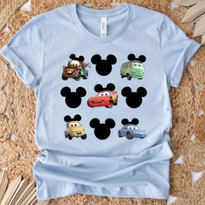 Pu&ograve; includere: Maglietta blu chiaro con una stampa grafica di orecchie di Topolino e personaggi di Cars. I personaggi includono Saetta McQueen, Mate e Mate il carro attrezzi.